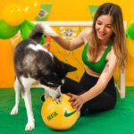 mulher-sentada-brincando-com-cachorro-tema-futebol-brasil
